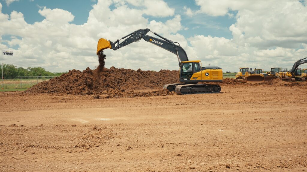 John Deere 210 P-Tier mid-size excavator moving dirt